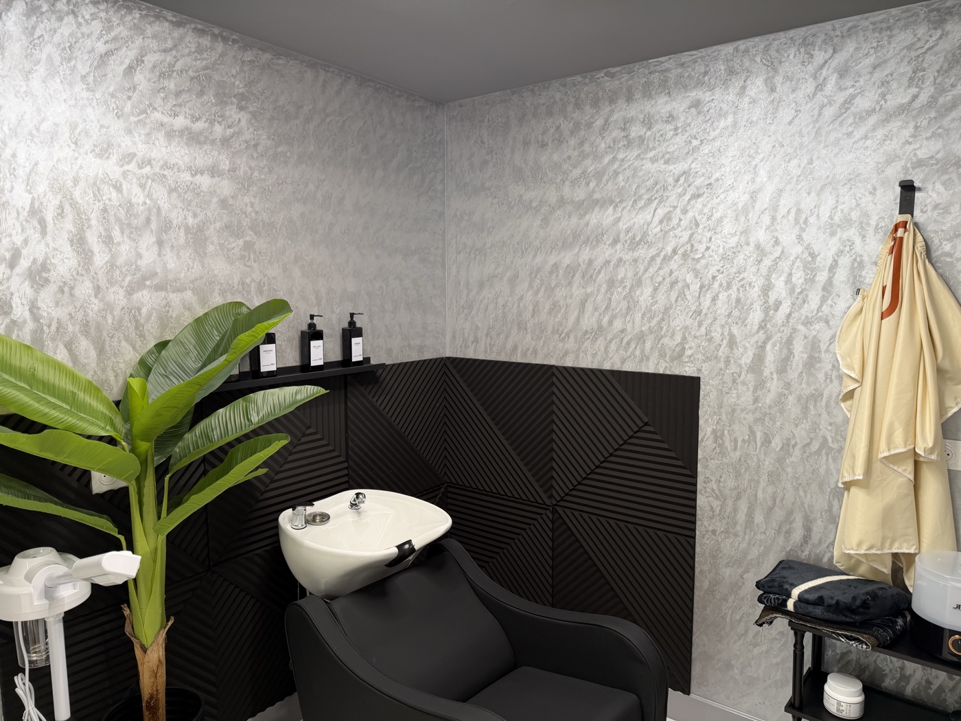 Espace lavage avec bac shampooing et mur acoustique 3D noir — salon Rijal